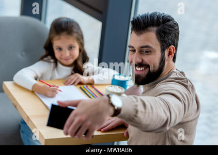 smiling father taking selfie of him and daughter in cafe Stock Photo