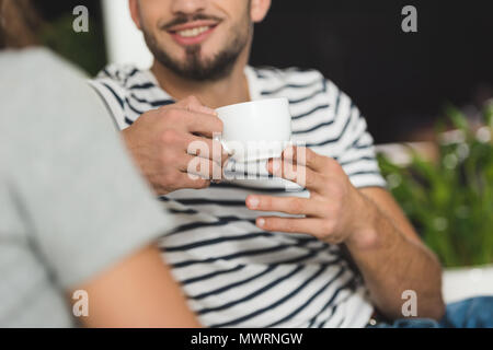 cropped shot of smiling young man drinking coffee on date with girlfriend Stock Photo