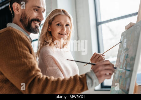 smiling mature students of art class painting together Stock Photo