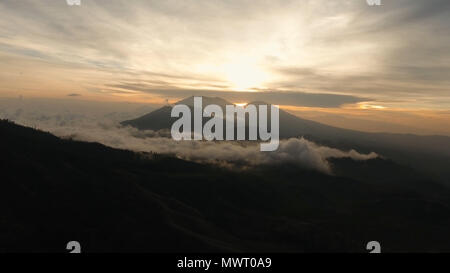 Beautiful sunset in the mountains on Jawa island, Indonesia. Aerial view of mountains landscape under sky with clouds, rainforest. Stock Photo