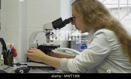 Doctor woman working with a microscope in Laboratory. Female scientist looking through a microscope in lab. Scientist using a microscope in a laboratory. Stock Photo
