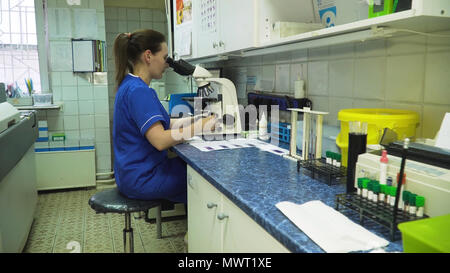 Woman lab assistant working with a microscope in Laboratory. Female scientist looking through a microscope in lab. Scientist using a microscope in a laboratory. Stock Photo