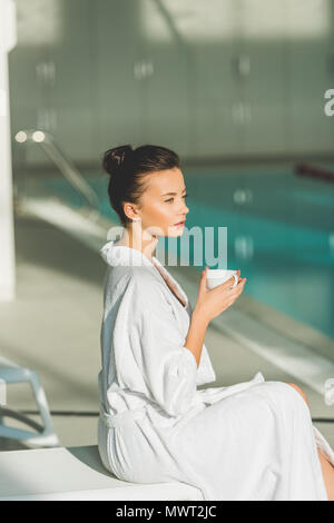 beautiful young woman in bathrobe with cup of coffee at spa Stock Photo