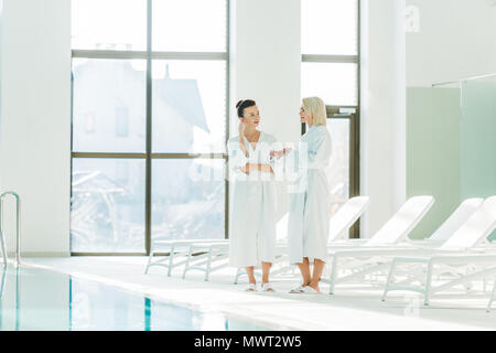 beautiful young women in bathrobes talking at spa center Stock Photo