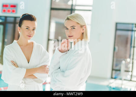 beautiful young women standing in front of swimming pool at spa center and looking at camera Stock Photo