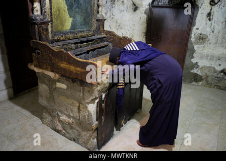 An Ethiopian Orthodox Christian pilgrim prays over the old wooden altar inside the Syriac Orthodox Chapel of Saint Joseph of Arimathea and Saint Nicodemus also called Jacobite chapel inside the Church of Holy Sepulchre in the Christian quarter East Jerusalem Israel Stock Photo