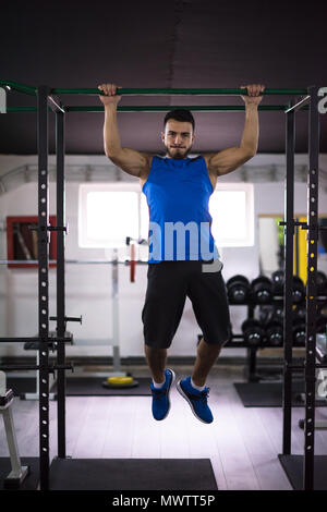 young muscular man doing pull ups on the horizontal bar as part of Cross fitness Training Stock Photo