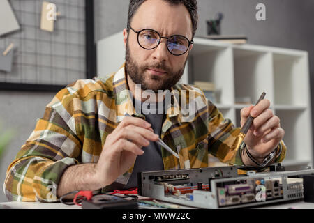 repairman using multimeter while fixing computer Stock Photo