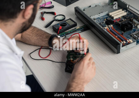 cropped image of man using multimeter while testing hard disk drive Stock Photo
