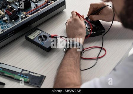 cropped image of man using multimeter with testing hard disk drive Stock Photo