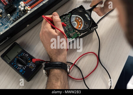 cropped image of repairman using multimeter while testing hard disk drive Stock Photo