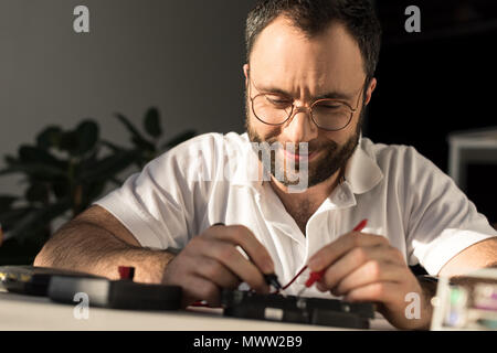 smiling man using multimeter while fixing pc Stock Photo