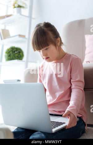 Kid with down syndrome using laptop Stock Photo
