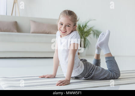 Caucasian lovely kid girl 5 years old, sitting barefoot on yoga mat,  stretching arms, looking confidently at camera 22971720 Stock Photo at  Vecteezy