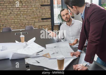 successful architects brainstorming over building plans at office Stock Photo