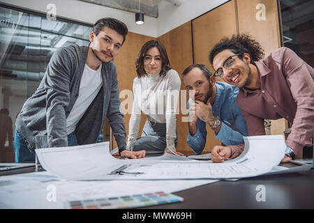 group of successful architects discussing plans and looking at camera at office Stock Photo