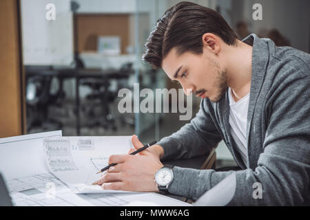 handsome young architect drawing building plans at office Stock Photo