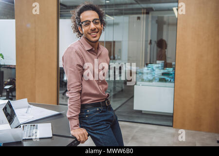 handsome young architect leaning back on workplace at office Stock Photo