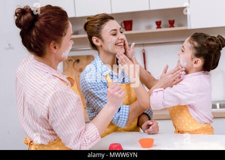 three generations of happy women playing with flour at kitchen Stock Photo