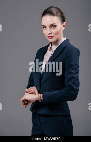 beautiful adult businesswoman checking time on wristwatch isolated on grey Stock Photo