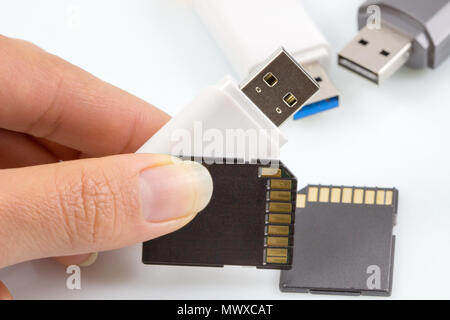 Hand holding usb stick, usb flash drive and memory card on white background. Stock Photo
