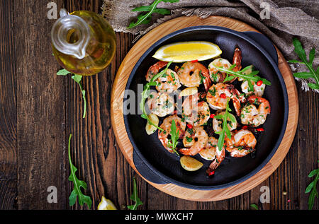 Prawns Shrimps roasted in garlic butter with lemon and parsley on wooden background. Healthy food. Top view. Flat lay. Stock Photo