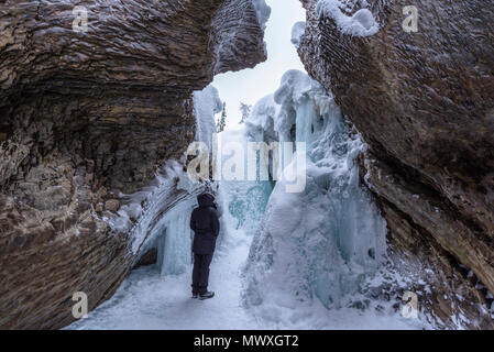 Young woman standing in front of ice and rock formations at Natural Bridge, Yoho National Park, UNESCO, British Columbia, The Rockies, Canada Stock Photo