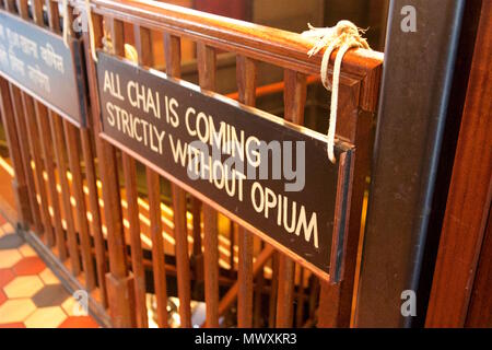 'All chai is coming strictly without opium' sign hanging by rope off a wooden bannister inside Dishoom, an indian restaurant in Shoreditch, London Stock Photo