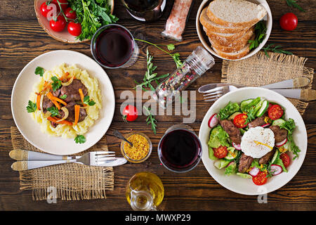 Fried chicken liver with vegetables and garnish of mashed potatoes. Warm salad from chicken liver, radish, cucumber, tomato and egg poached.  Served t Stock Photo