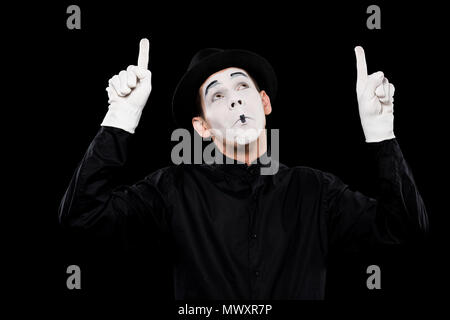 grimacing mime pointing on something isolated on black Stock Photo