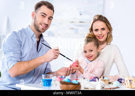 Father and daughter smiling while painting Easter eggs Stock Photo