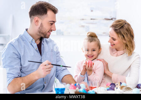 Child holding Easter egg by smiling parents Stock Photo