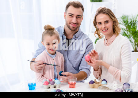 Child and parents coloring eggs for Easter Stock Photo