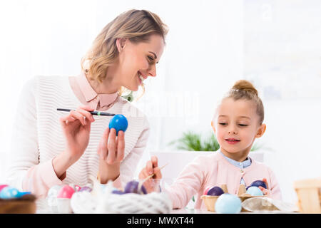 Mother and daughter having fun while painting Easter eggs Stock Photo