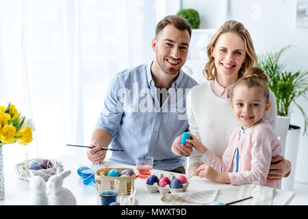 Smiling family with daughter coloring Easter eggs Stock Photo