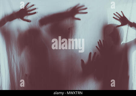 blurry scary silhouettes of people touching frosted glass with hands Stock Photo