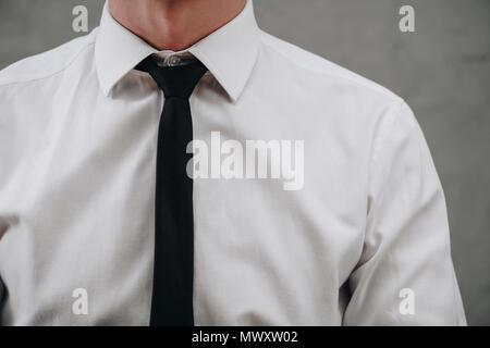 cropped shot of businessman in white shirt and black necktie on grey Stock Photo