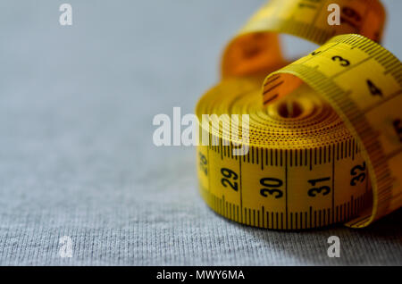 https://l450v.alamy.com/450v/mwy6ma/the-measuring-tape-of-yellow-color-with-numerical-indicators-in-the-form-of-centimeters-or-inches-lies-on-a-gray-knitted-fabric-background-concept-fo-mwy6ma.jpg