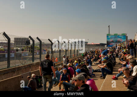 19-20th May 2018. Le Mans, France.  Behind the scenes at the MotoGP.  Spectators overlooking the race circuit's start finish line.  A big screen at the end of the grand stand is ready to relay the close up action of the days racing.  It's a bright sunny day with a blue sky. Stock Photo