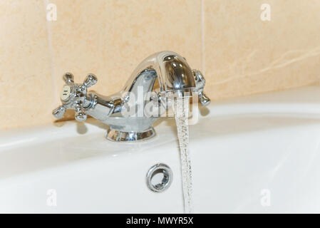 Clean drinking water flows from a steel tap in the bathroom Stock Photo