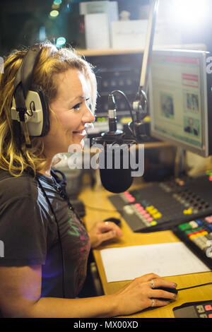 White British female radio DJ inside recording studio at work Stock Photo