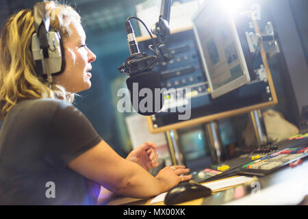 White British female radio DJ inside recording studio at work Stock Photo