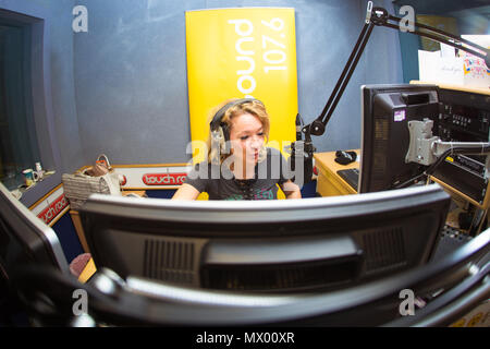 White British female DJ working inside recording studio with headphones Stock Photo