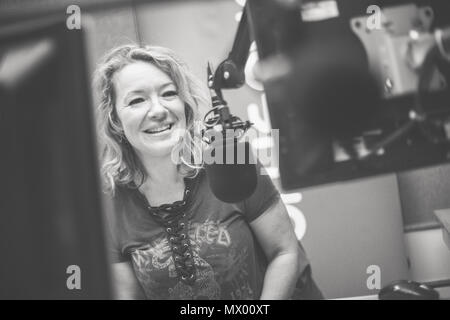 White British female DJ working inside recording studio with headphones Stock Photo