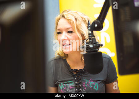 White British female DJ working inside recording studio with headphones Stock Photo