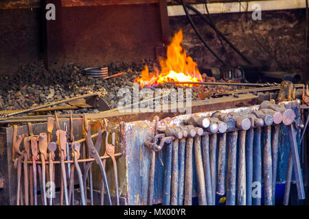 Blacksmith at work at the anvil in the old smithy at Cockington Forge in Devon. Stock Photo