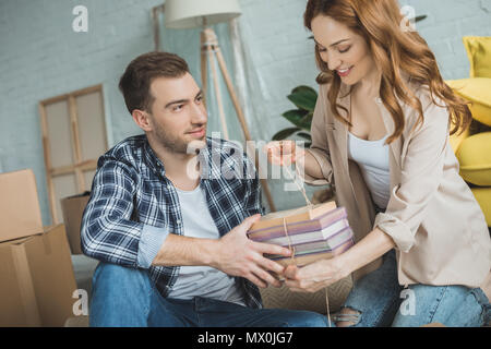 happy young couple packing books while moving home Stock Photo