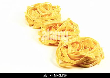 Three traditional italian pasta tagliatelle nests isolated on white background. Stock Photo