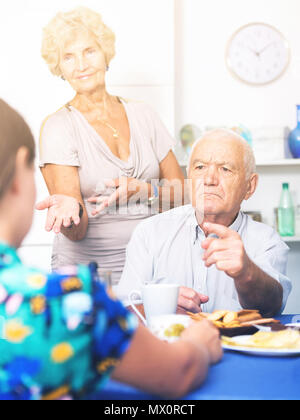 Stressed senior couple having conversation with female over cup of coffee at home Stock Photo