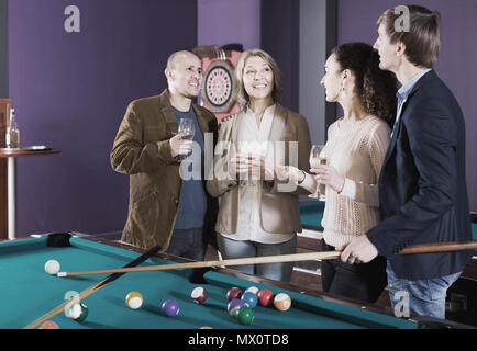 happy american mature and young couples hanging out in billiard club together Stock Photo